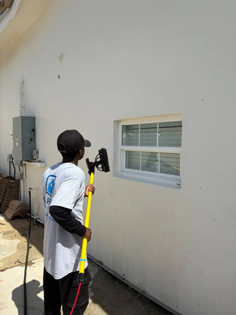 Gulfshine technician brushing an exterior wall beside a window