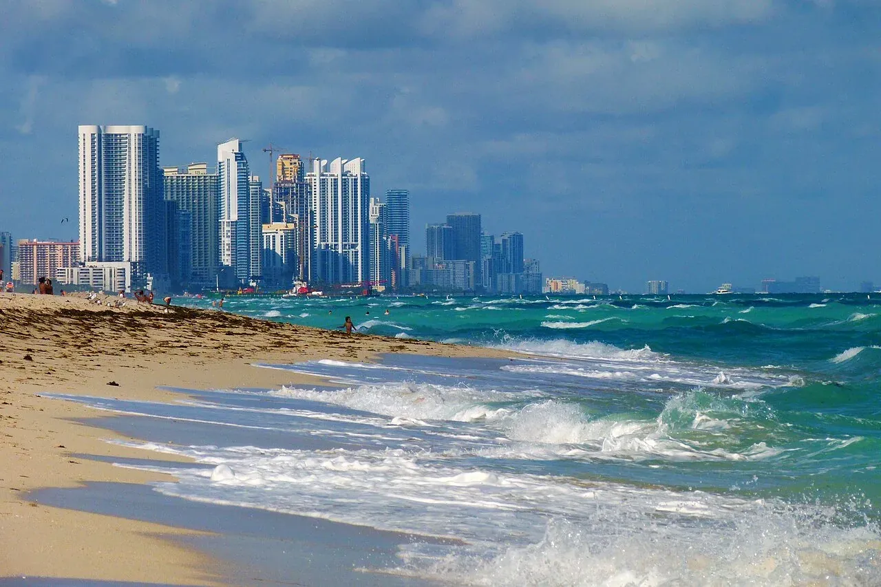 Beachfront condo tower skyline behind sand and surf, Sunny Isles Beach