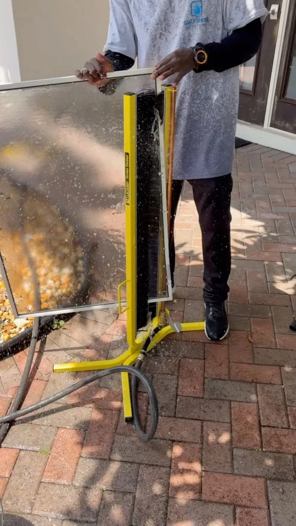 Gulfshine technician washing a window screen with professional equipment